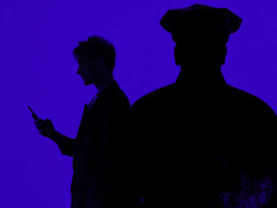 Silhouettes of person checking phone and police officer watching in foreground