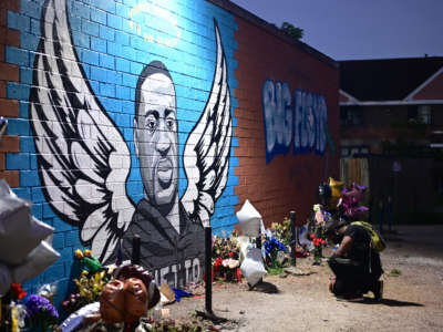 A man pays his respects and kneels in front of a mural of George Floyd in Houston, Texas, on June 8, 2020.