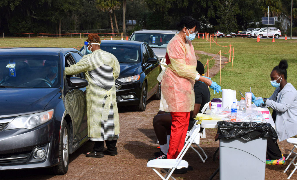 A health care worker collects a swab sample from a person in a car at a testing site at Edwards Field in Apopka, Florida, amid an Omicron variant surge in the state.