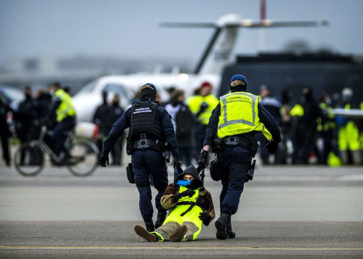 The Marechaussee arrest a protester at 'SOS for the climate' action at Schiphol Airport - Netherlands OUT 