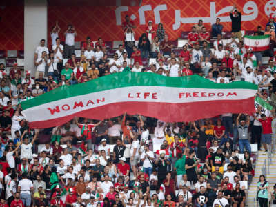 Iranian fans hold up a banner that says "Woman Life Freedom" during the FIFA World Cup Qatar 2022 Group B match between England and Iran at Khalifa International Stadium on November 21, 2022, in Doha, Qatar.