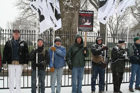 Veterans and peace activists form a line at the barricade in front of the White House fence.