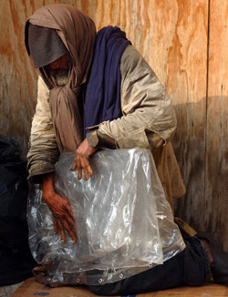 A homeless man in Memphis, Tennessee slowly and with great care folds plastic sheeting he uses to stay warm. Photo: John Mottern