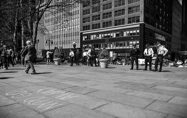 Police officers wait in Bryant Park early Wednesday morning near a sidewalk message written for their benefit. (Photo: Craig O'Connor)