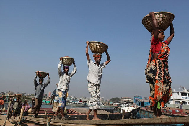 Laborers carry sand from a cargo boat on the river bank in Gabtoli, Dhaka.