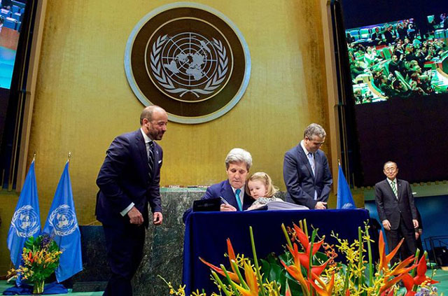 US Secretary of State John Kerry signs the Paris Agreement at the UN in New York while holding granddaughter Dobbs Higginson on his lap. Scientists warn that the agreement is insufficient to prevent disastrous climate change. (Photo courtesy of US Department of State)