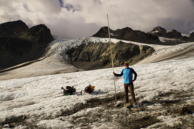 The author holds a glacier survey stake on Alaska's Gulkana Glacier. The stake was placed in April, at which time the tip of the stake was just inches below the surface of the snowpack. The snowpack is gone, along with roughly three feet of glacial ice. (Photo: Louis Sass)