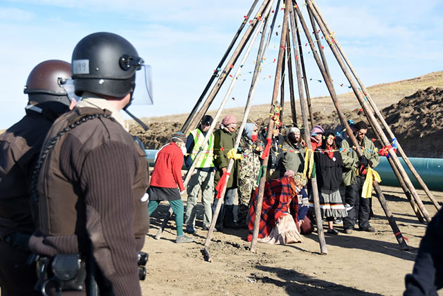 Gathered under tipi poles at the protest site in Standing Rock, a group of water protectors continue their demonstration after being told to leave by the police on October 10, 2016. (Photo: Ellen Davidson)