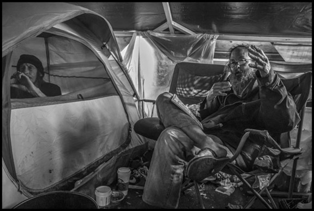 Mike Lee and Mike Zint (in the tent) in the camp outside the Berkeley Post Office, originally established to protest the sale of the Main Post Office building. The Post Office Police demolished the camp and evicted the residents a few weeks after the photo was taken. (Photo: David Bacon)