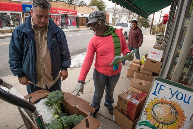 Four Season Produce transporter, Jeff Martin (blue jacket) looks on as broccoli is inspected by a Glut worker-owner of this cooperative store, that serves the Mount Rainier, Maryland community, on Tuesday, March 3, 2015.
