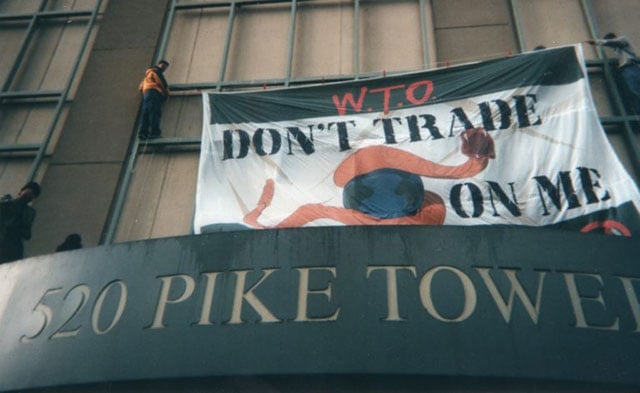 Protestors put up a sign at a 1999 WTO protest in Seattle, Washington. (Photo by Ph0kin licensed under the Creative Commons Attribution-Share Alike 2.0 generic license)