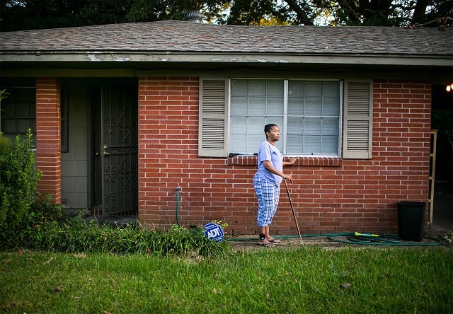 Tennie White stands in front of her home.