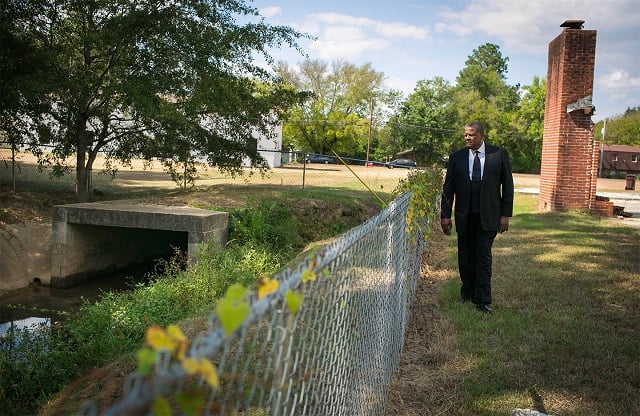 Rev. Steve Jamison walks alongside a polluted ditch that flows through the property of Maranatha Faith Center in Columbus, Mississippi. The ditch is where Jamison first discovered creosote flushed out from the old Kerr-McGee site. 