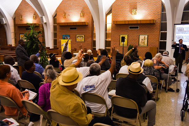 Public meeting attendees raise their hands to question Arcadis representative Scott Hoffeld. (Photo: Michael Stein)