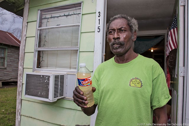 Eddie Sanders holds a bottle he filled at home to show the poor condition of his tap water. (Photo: Julie Dermansky)