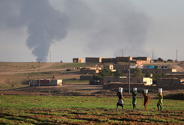 Villagers walk to collect water after troops from the Syrian Democratic Forces, a coalition of Kurdish and Arab forces, retook a town on November 11, 2015 near Hasaka, in the autonomous region of Rojava, Syria. (Photo: John Moore / Getty Images)