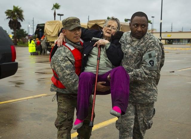 Texas Army National Guard members Sergio Esquivel, left, and Ernest Barmore carry 81-year-old Ramona Bennett after she and other residents were rescued from their Pine Forest Village neighborhood due to high water from Hurricane Harvey August 29, 2017 in Houston, Texas. (Photo by Erich Schlegel/Getty Images)