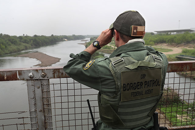 A US Border Patrol agent scans the US-Mexico border while on a bridge over the Rio Grande on March 13, 2017 in Roma, Texas. In the eyes of the nation-state, a person migrating because of climate reasons is meaningless, says author and journalist Todd Miller. (Photo: John Moore / Getty Images)