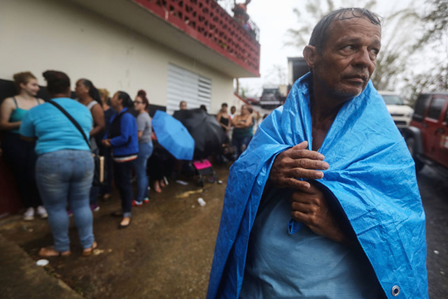 Arian Rodriguez covers himself with a tarp as residents wait in the rain to register with FEMA more than two weeks after Hurricane Maria hit the island, on October 9, 2017, in Jayuya, Puerto Rico. (Photo: Mario Tama / Getty Images)