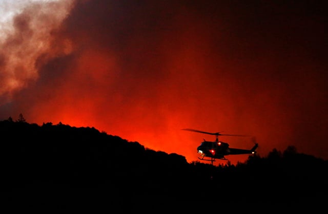A helicopter prepares to drop water on a fire that threatens the Oakmont community along Highway 12 in Santa Rosa on October 13, 2017. Early morning mandatory evacuations happened on Adobe Canyon Road and Calistoga Rd. (Photo:Genaro Molina / Los Angeles Times via Getty Images)