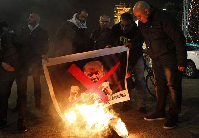 Palestinian protesters burn pictures of US President Donald Trump at the manger square in Bethlehem on December 5, 2017. US President Donald Trump told Palestinian leader Mahmoud Abbas in a phone call that he intends to move the US embassy from Tel Aviv to Jerusalem, Abbas's office said. (Photo: MUSA AL SHAER / AFP / Getty Images)