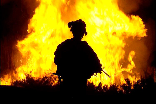 A US army sergeant watches flames rise into the night sky after setting canal vegetation ablaze in Tahwilla, Iraq, July 30, 2008. (Photo: The US Army)