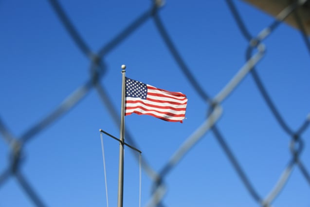 American flag behind a chain link fence.