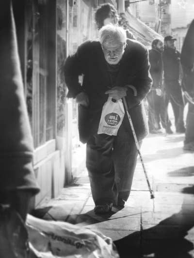An elderly man passes a crowd of demonstrators while leaving a one euro shop in Greece, September 2012.