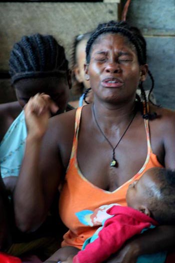 A woman cries as she recalls the murder of her family members when they were driven from their homes by paramilitaries. Today she lives in an Afro-Colombian squatter community, the Brisas de los Angeles barrio, controlled by paramilitaries as well. (Photo: David Bacon)