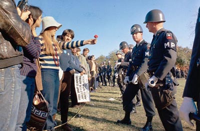 A female demonstrator offers a flower to military police on guard at the Pentagon during an anti-Vietnam demonstration. Arlington, Virginia, October 1967.