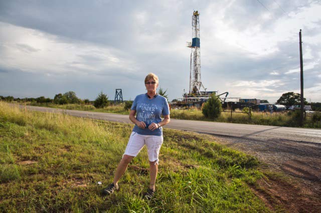 Angela Spotts across from a drilling rig at a hydraulic fracturing site near her home. ©2014 Julie Dermansky