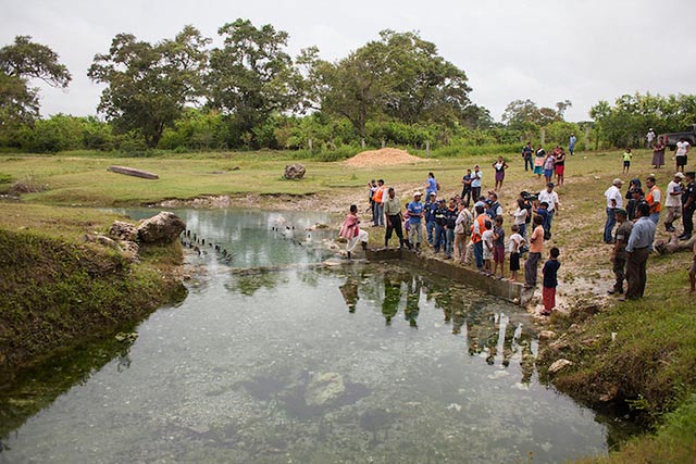 Sayaxché residents gather by a stream during a visit in July by Guatemalan government and UN officials to communities affected by the mass fish die-off in June. (Photo by CONRED Guatemala)