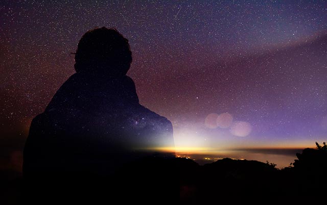 Man's silhouette over starry dawn