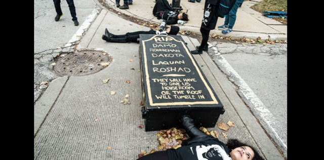 Protesters lie down linked to a casket lockbox inscribed with names of men who have been killed by the police. (Photo: Sarah Jane Rhee)