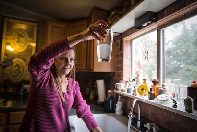 Shelly Perdue holds up a glass of contaminated water in Parker County, Texas. Her home is across the street from an Range Recources fracking site. (Photo: ©Julie Dermansky)
