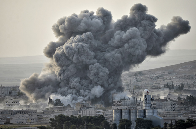 An explosion after an apparent US-led coalition airstrike on Kobane, Syria, as seen from the Turkish side of the border, near the Suruc district, on October 13, 2014. (Photo via Shutterstock)