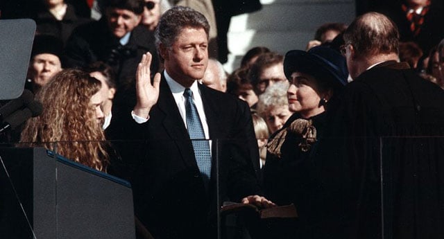 Bill Clinton, standing between Hillary Rodham Clinton and Chelsea Clinton, taking the oath of office of President of the United States on January 20, 1993. Clinton ran for president as a champion of the working class, but largely abandoned their economic interests while in office – preferring Wall Street to Main Street — beginning with his signing of NAFTA.