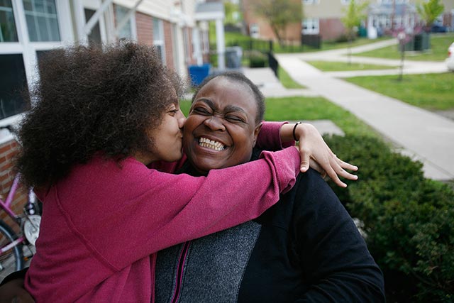 Leatha, 13 years old, gives her mom, Angela Scott, a kiss outside their home at the Ezra Prentice Homes. (Photo: Earthjustice)