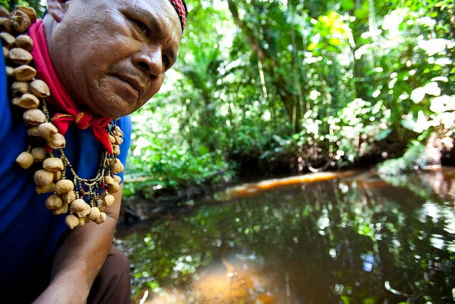 Cofan Indigenous leader Emergildo Criollo looks over an oil contaminated river near his home in northern Ecuador.