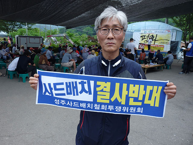 A representative of the Korean Confederation of Trade Unions holds an anti-THAAD banner at a demonstration in Soseong-ri, Seongju County, South Korea. (Photo: Jon Letman)