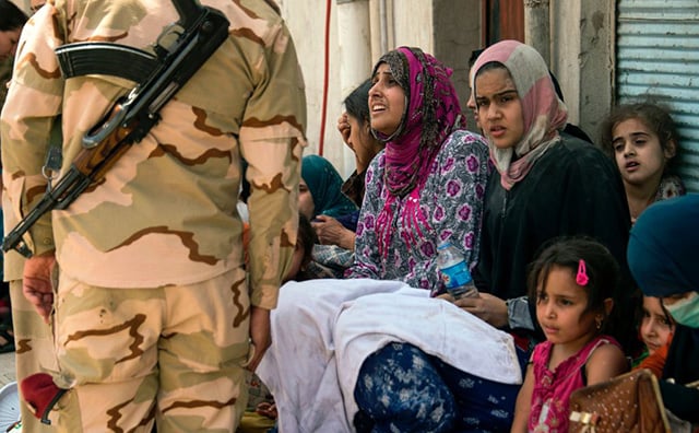 Iraqi women, who fled the fighting between government forces and Islamic State jihadists in the Old City of Mosul, sit in waiting in the city's western industrial district prior to being relocated, on July 8, 2017. (Photo: Fadel Senna / AFP / Getty Images)